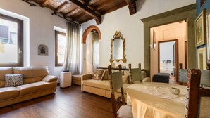 Una sala de estar amoblada con piso de madera, un sofá, una silla, una mesa y un espejo.