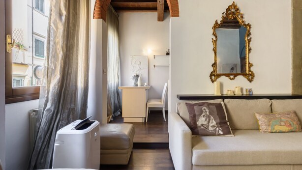 Una sala de estar con sofá, una mesa de centro, chimenea y un espejo grande en la pared.
