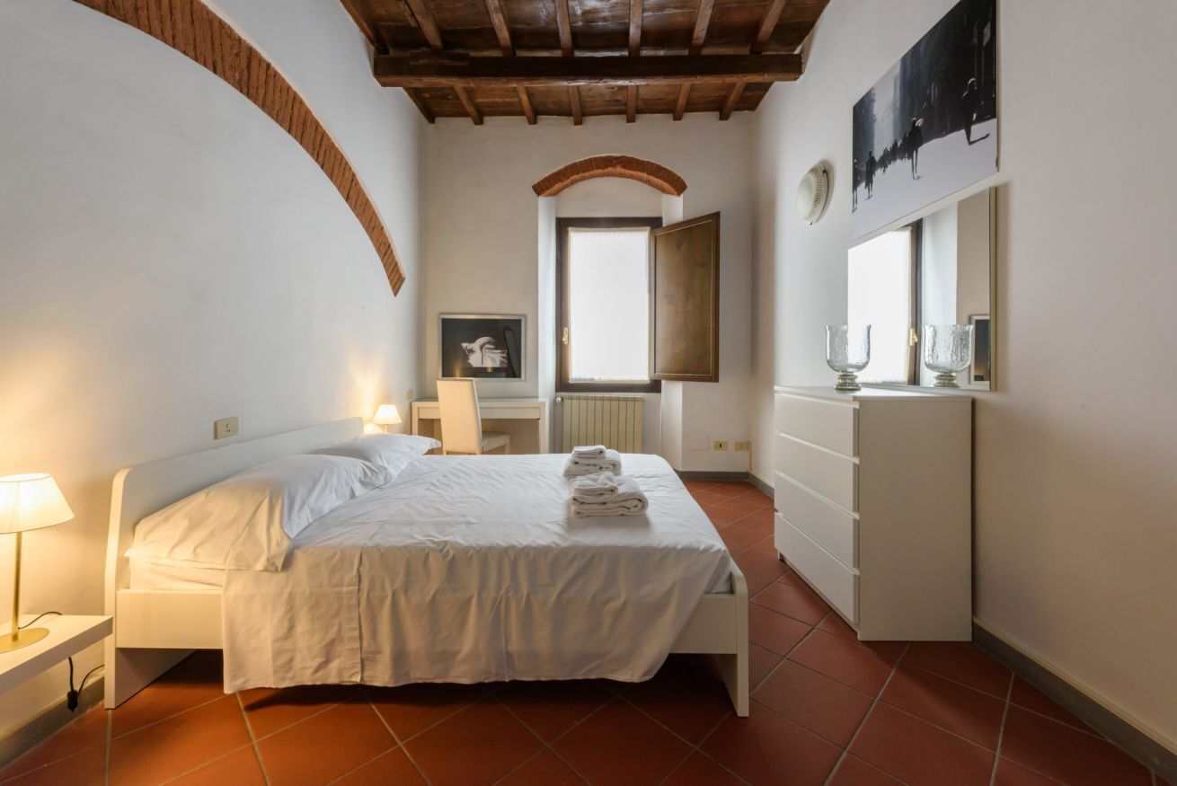 Una camera da letto con un letto, un comodino, una cassettiera, una finestra e un quadro appeso al muro.
