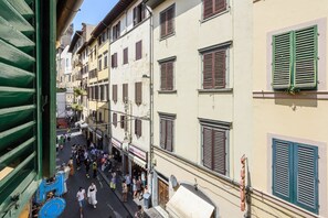 Une rue étroite bordée d’immeubles à plusieurs étages, dont certains arborent des enseignes bien visibles.