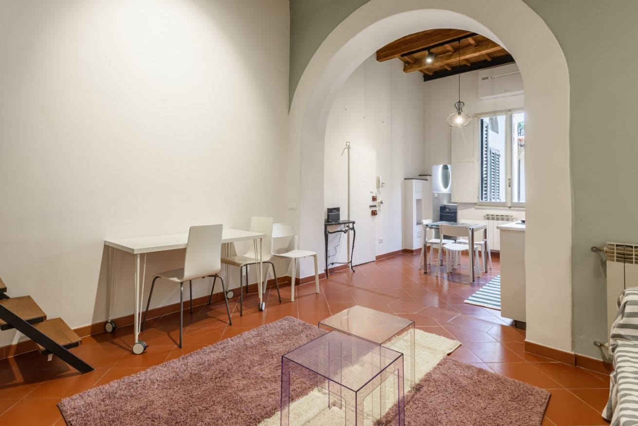 Un soggiorno moderno con angolo pranzo, cucina e una scala.