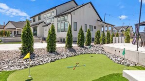 Un edificio moderno con un césped cuidado y una zona de práctica de golf.