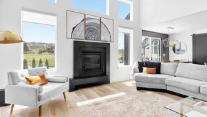 Una sala moderna con chimenea, ventanas amplias y vistas al exterior.