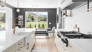 Una cocina moderna con una isla grande, un comedor con banco y vistas al exterior.