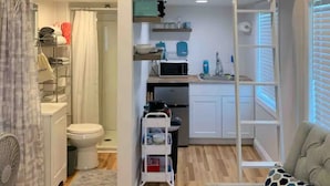 Un espace de vie compact comprenant un coin cuisine, une petite salle de bain et un espace détente.
