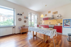 A modern kitchen with a dining table, red cabinets, and a view through an open door.