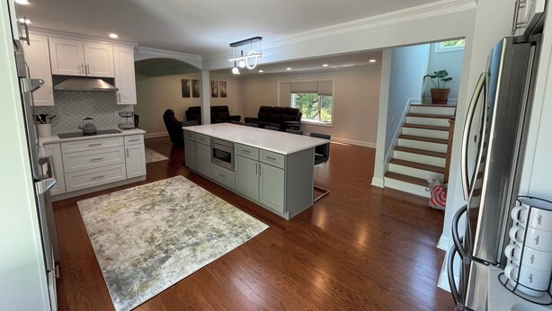 A spacious kitchen with a central island, wooden flooring, and a built-in oven. - Modern Getaway Retreat House on 2 Acres (Poughkeepsie)