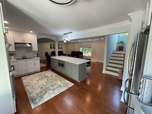 A spacious kitchen with a central island, wooden flooring, and a built-in oven.
