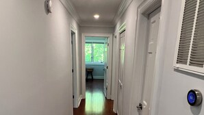 A hallway with wooden flooring, white walls, and doors leading to rooms. - Modern Getaway Retreat House on 2 Acres (Poughkeepsie)