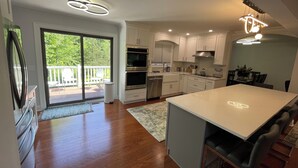 A modern kitchen with white cabinets, stainless steel appliances, and a large island. - Modern Getaway Retreat House on 2 Acres (Poughkeepsie)