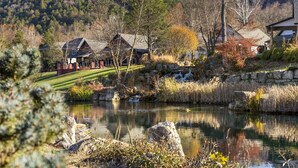 A lakeside property with a stone bridge, a pond, and houses in the background.