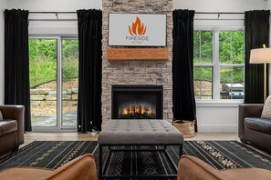 Uma sala de estar com lareira de pedra, dois sofás de couro, um tapete e uma placa acima da lareira com a inscrição 'Fireside Retreat'.