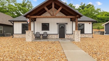 A building with a stone foundation, a wooden porch, and two Adirondack chairs.