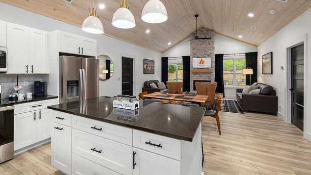 A modern kitchen with white cabinets, a central island, stainless steel appliances, and pendant lighting.