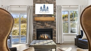 Una sala de estar acogedora con chimenea de piedra, asientos confortables y un amplio ventanal con vistas al exterior.