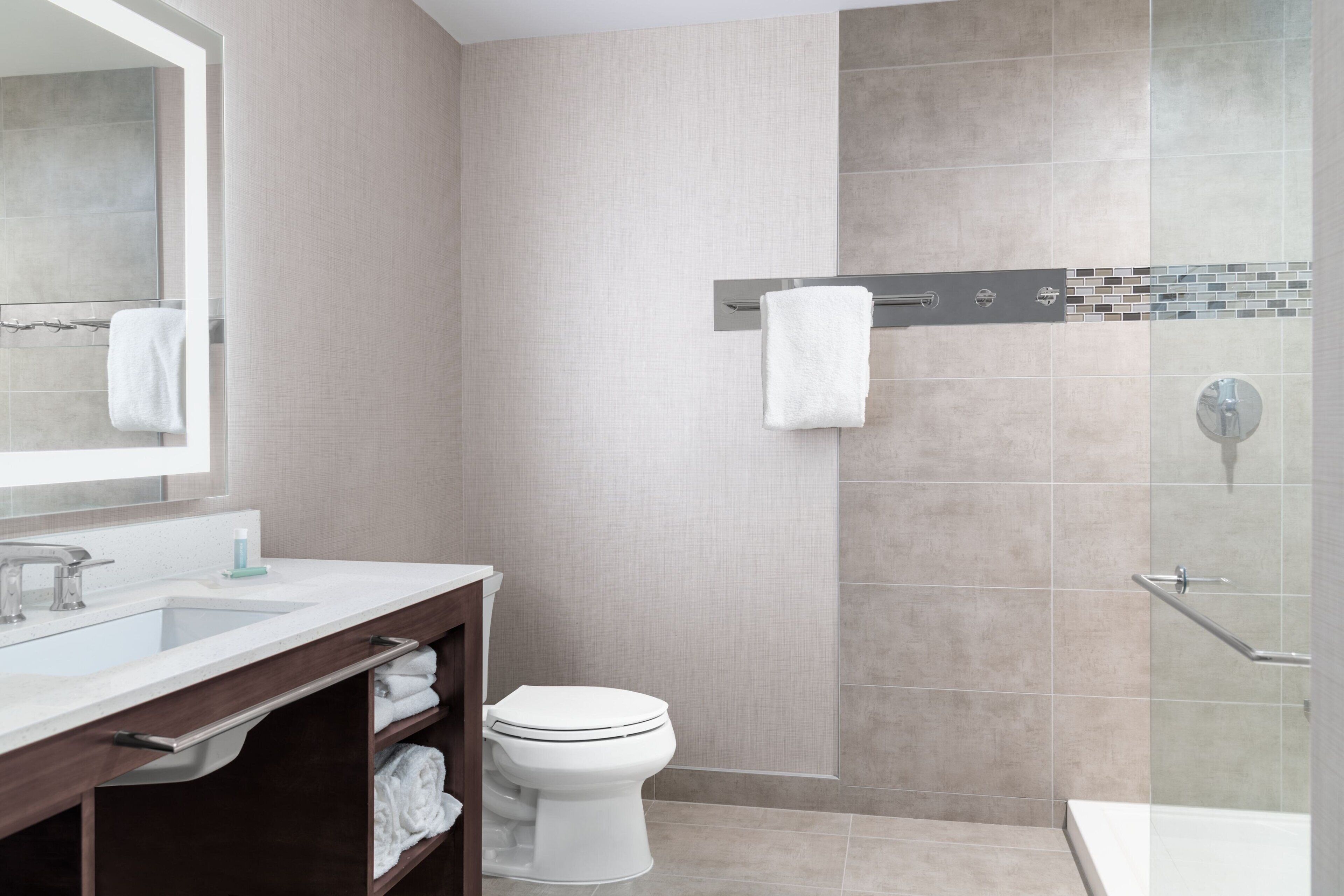 Un baño moderno con lavamanos, espejo, inodoro y zona de ducha.