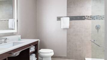 Un baño moderno con lavamanos, espejo, inodoro y zona de ducha.