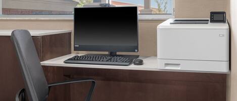 A modern office desk with a computer, keyboard, and mouse, a printer, and a chair.