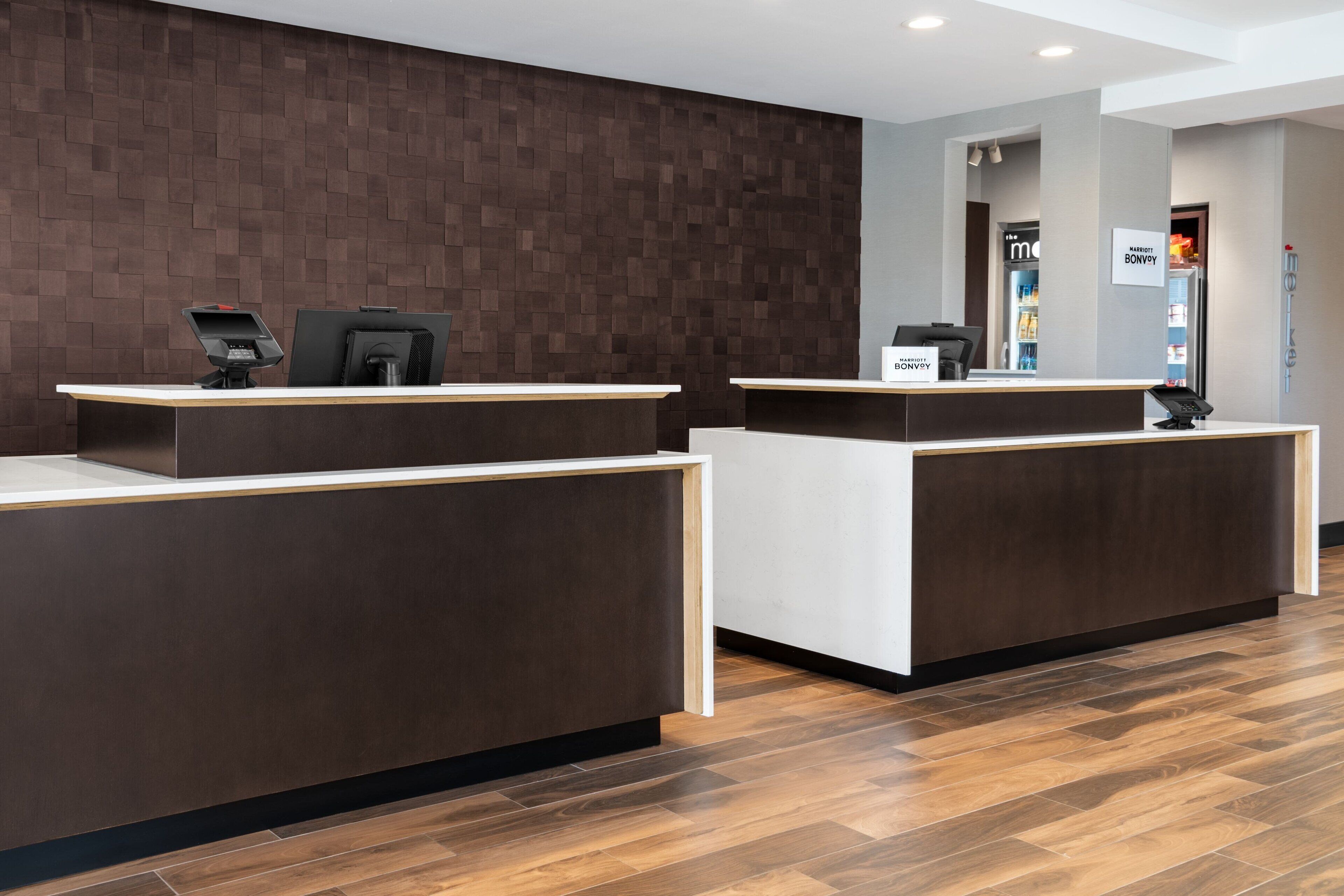 A reception area with two reception desks, a brown wall, and a wooden floor.