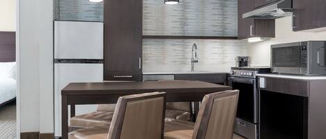 A modern kitchen with dark cabinetry, a central island with chairs, a microwave, and an oven.