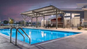Una piscina con zona de estar cubierta y un patio cercado.