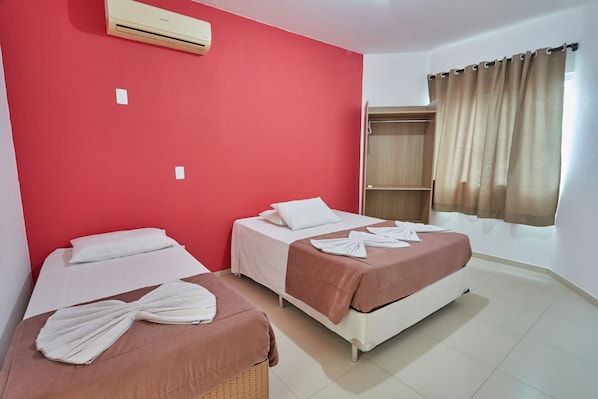 A hotel room with two beds, red walls, a wardrobe, and a window with curtains. - Hotel Monte Libano (Florianópolis)