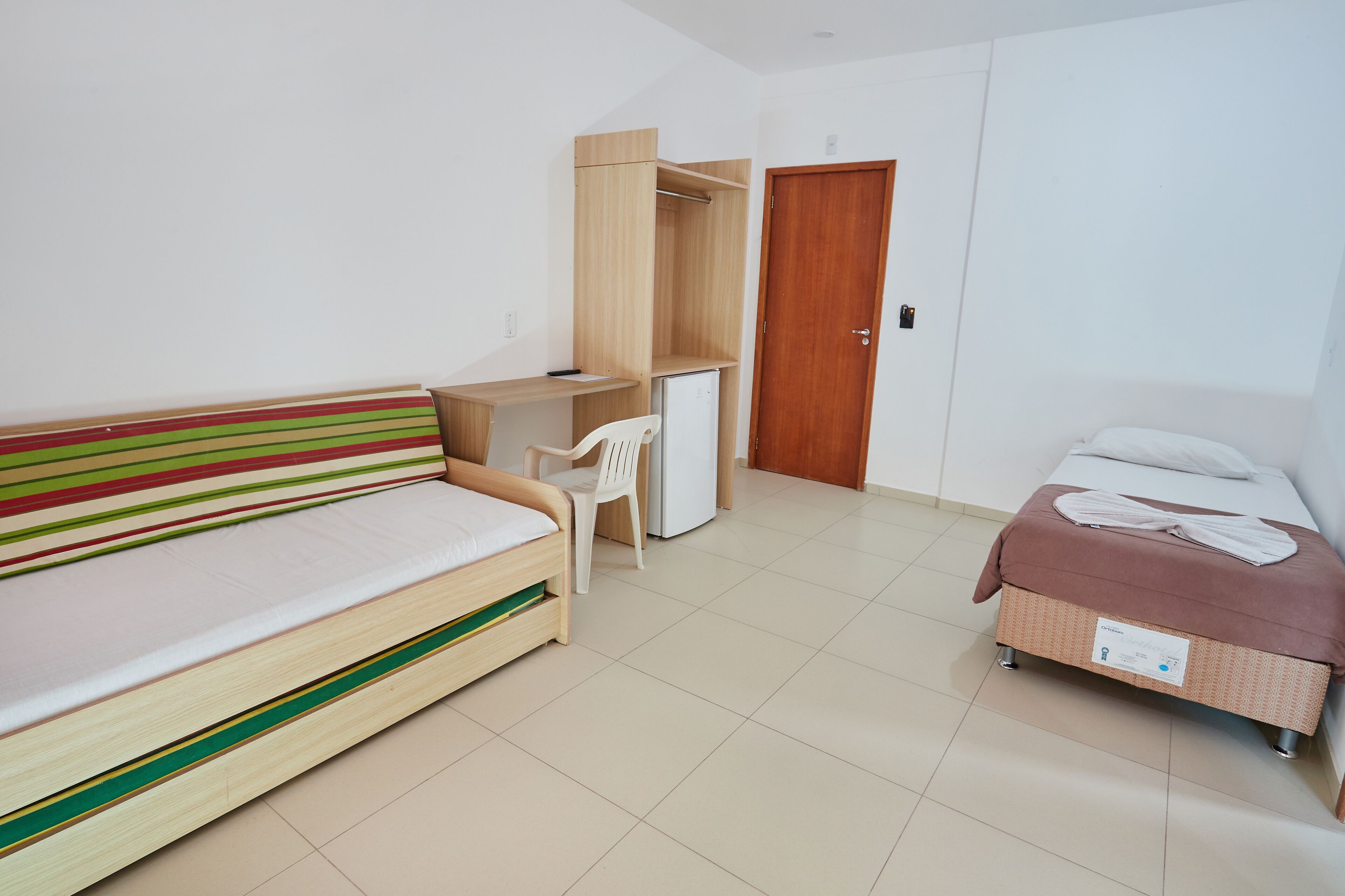 A bedroom with a bed, a desk, a chair, a wardrobe, and a door.
