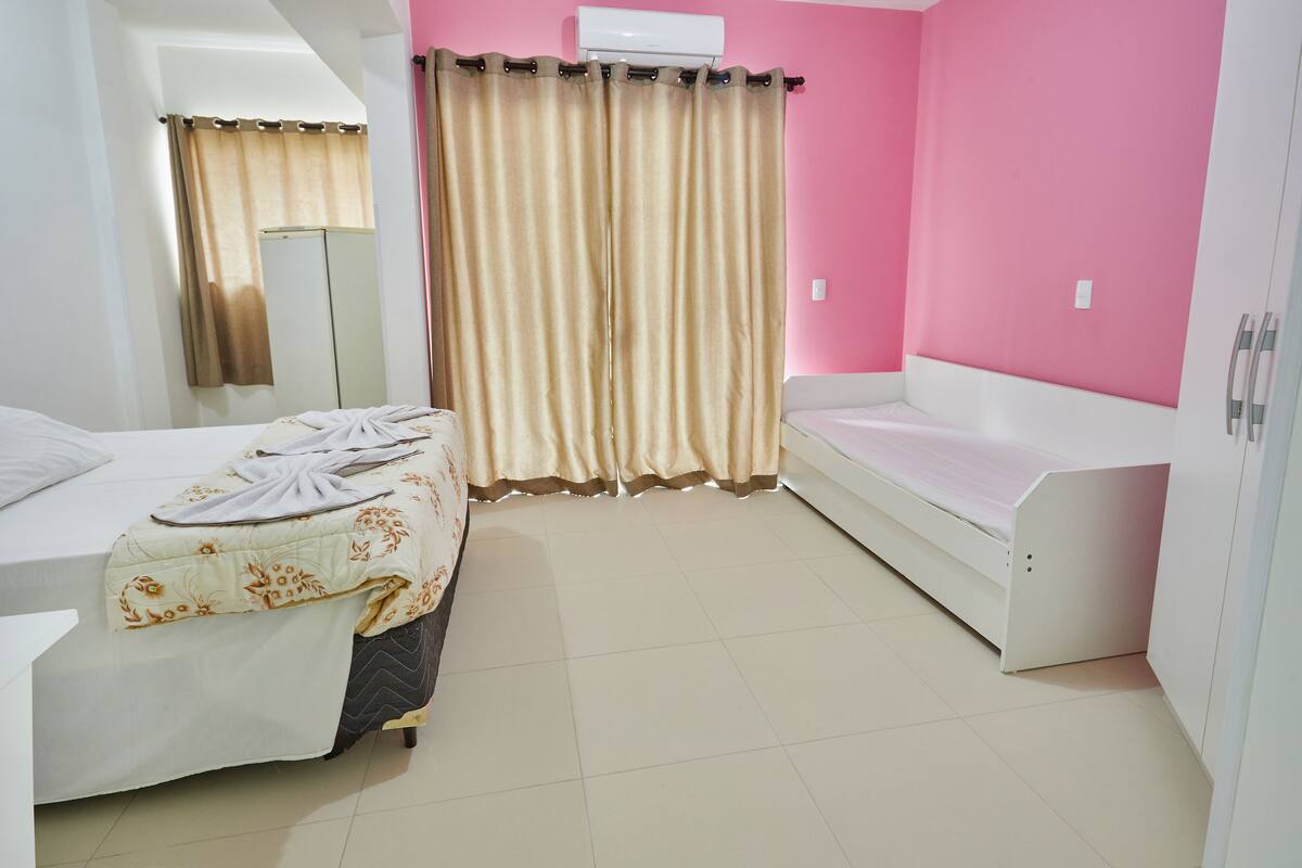 A bedroom with two beds, a wardrobe, a mirror, and a curtain.