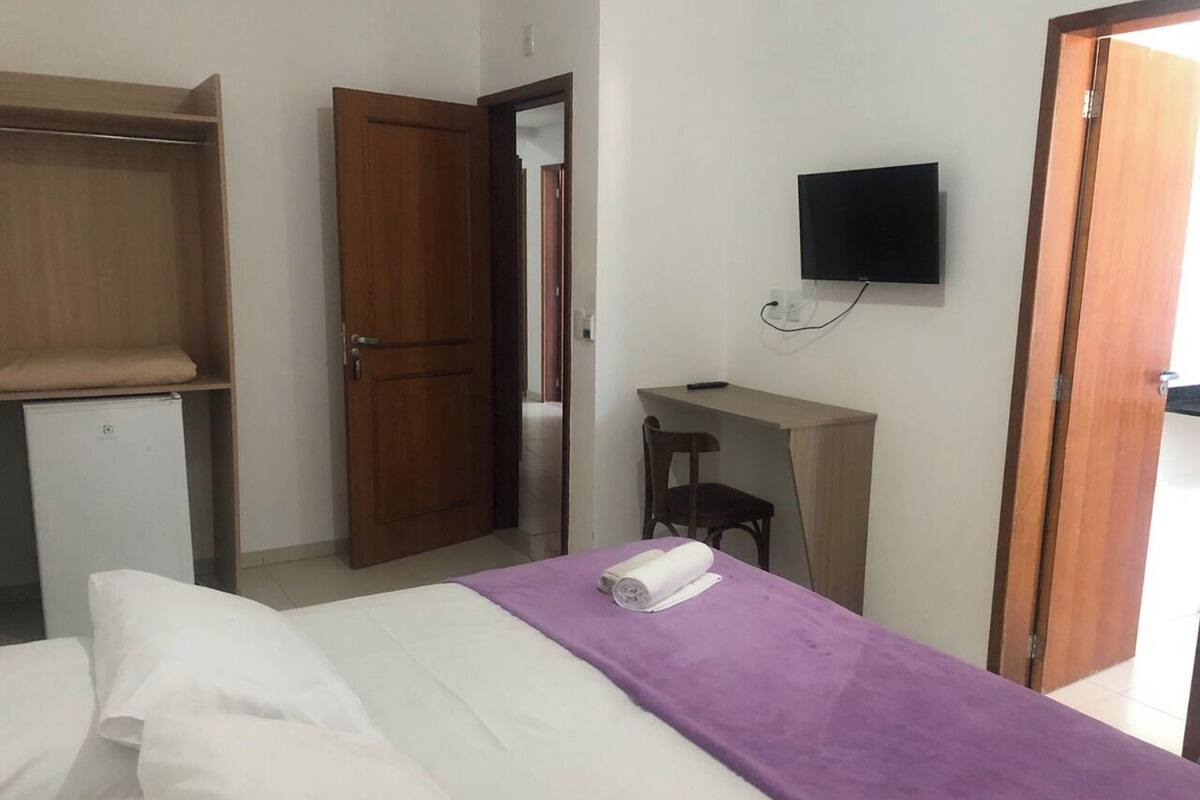 A hotel room with a bed, a desk, a television, and a wardrobe.