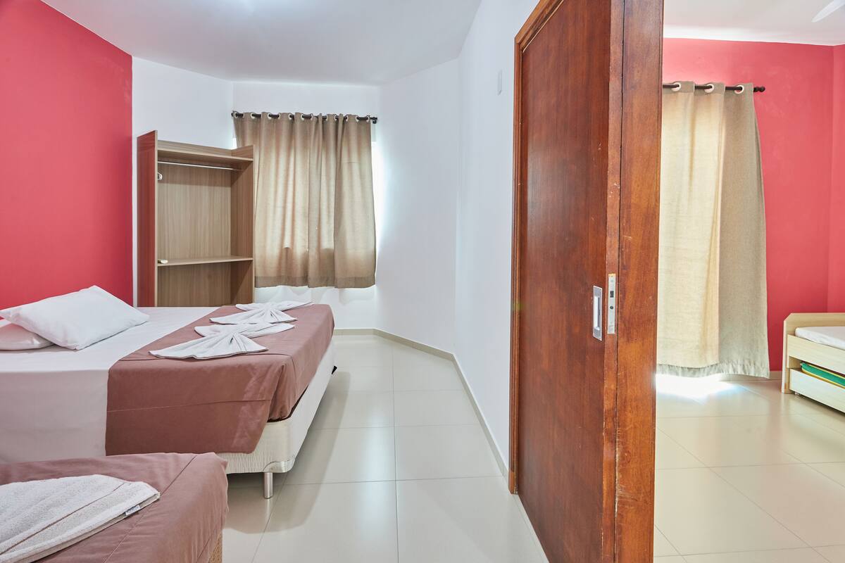 A hotel room with two beds, a wardrobe, and a bathroom.