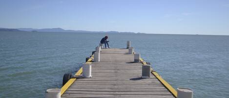 Un muelle de madera que se adentra en aguas tranquilas, con una persona al final.