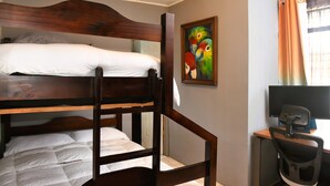 A bunk bed room with a desk and chair, a painting on the wall, and a window with curtains. - Papaya Dreams (San Juan)