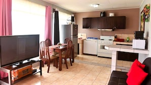 A compact living space with a dining area, kitchenette, and a TV. - Papaya Dreams (San Juan)