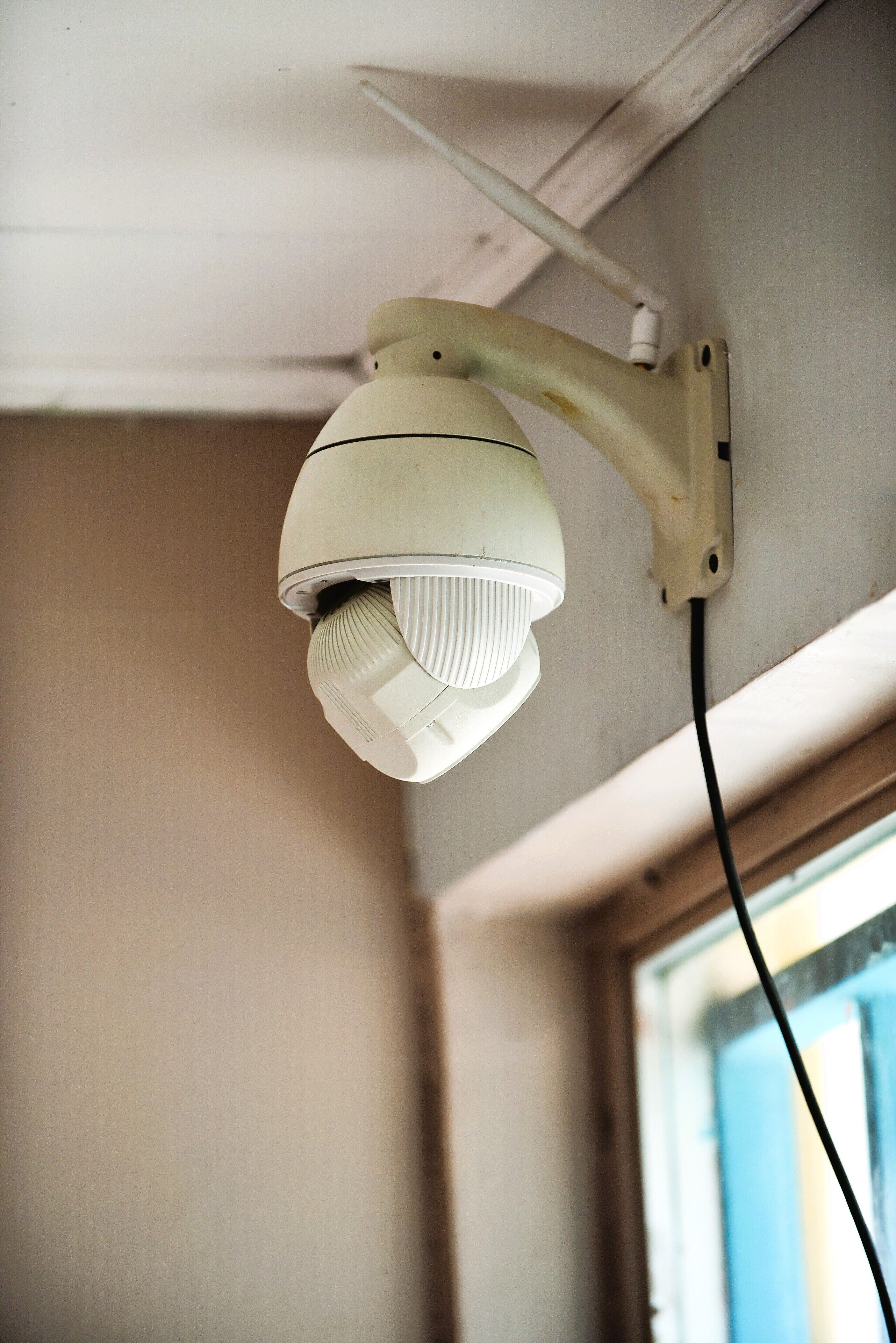 Uma câmera de segurança instalada no teto, com um cabo de alimentação visível.