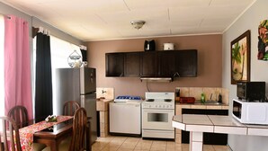 A compact kitchen with a dining area, featuring a stove, microwave, and cabinets. - Papaya Dreams (San Juan)
