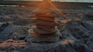 A stack of stones on a beach with the sun setting in the background. - The Inn at Woodsong Acres (Kingsville)