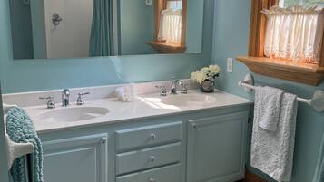A bathroom with two sinks, a large mirror, and a window with a wooden frame.