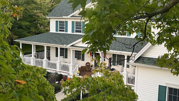 A two-story house with a porch and a small garden. - The Inn at Woodsong Acres (Kingsville)