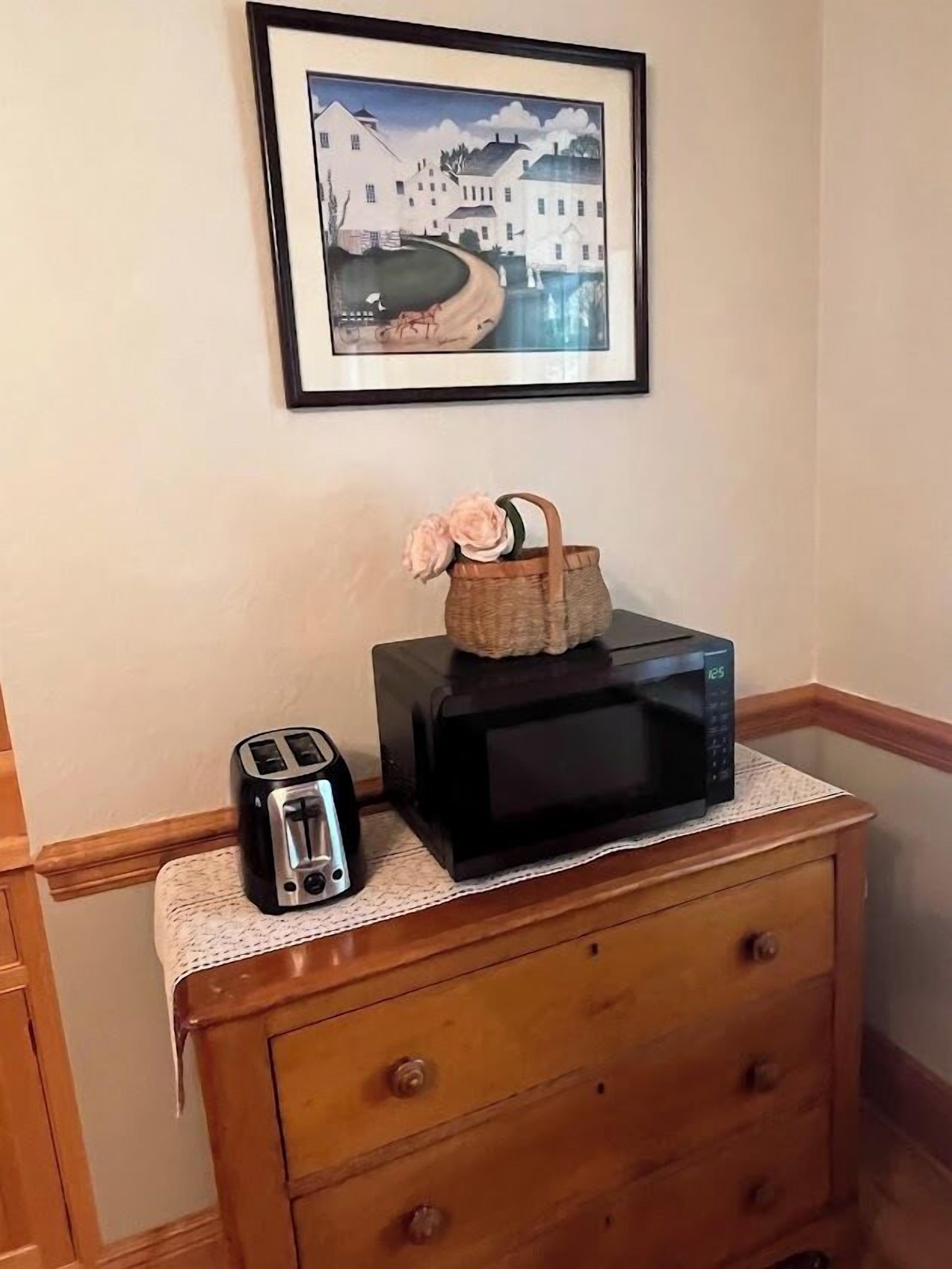 A kitchen counter with a toaster, a microwave, and a basket with flowers.