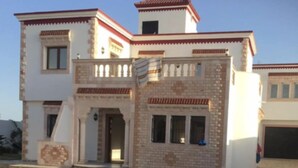 A two-story house with a brick facade, a balcony, and a garage. - Villa Romantique Avec Piscine à 5 min de la Plage (Djerba Midun)
