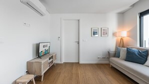 Ein modernes Wohnzimmer mit einer Couch, einem Fernseher, einer Lampe und einer Tür.