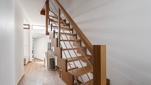 Una escalera moderna con escalones de madera y barandillas de metal, que sube a un piso superior.
