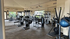 A spacious gym with various exercise machines, a blue medicine ball, and ceiling fans. - Chasing Sunsets in Cabo - Pacific Ocean Beachfront 1B/1B Luxury Junior Suite (Cabo San Lucas)