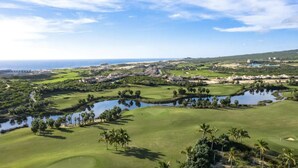 A golf course with multiple water hazards, palm trees, and a view of the ocean. - Chasing Sunsets in Cabo - Pacific Ocean Beachfront 1B/1B Luxury Junior Suite (Cabo San Lucas)