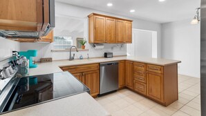 A modern kitchen with wooden cabinets, a dishwasher, a coffee machine, and a built-in oven.
