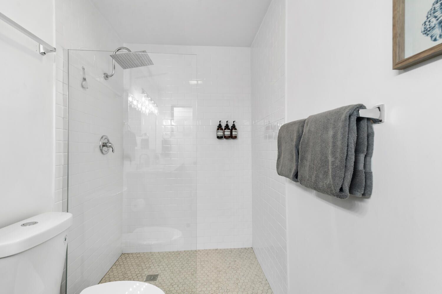 Une salle de bain moderne dotée d’une douche à parois de verre, de toilettes et d’un porte-serviettes.