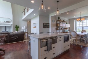 A spacious kitchen with a central island, pendant lighting, and a dining area with a view.