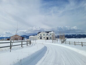 A snow-covered landscape with a large house, a wooden barn, and a fenced area. - Hearthstone Farm - Great Teton Views (Driggs)
