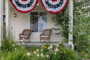 A porch with two wicker chairs, a window, and a flag.