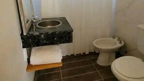 Un baño pequeño con techo de madera, un lavamanos con espejo, un inodoro y una cortina de ducha.